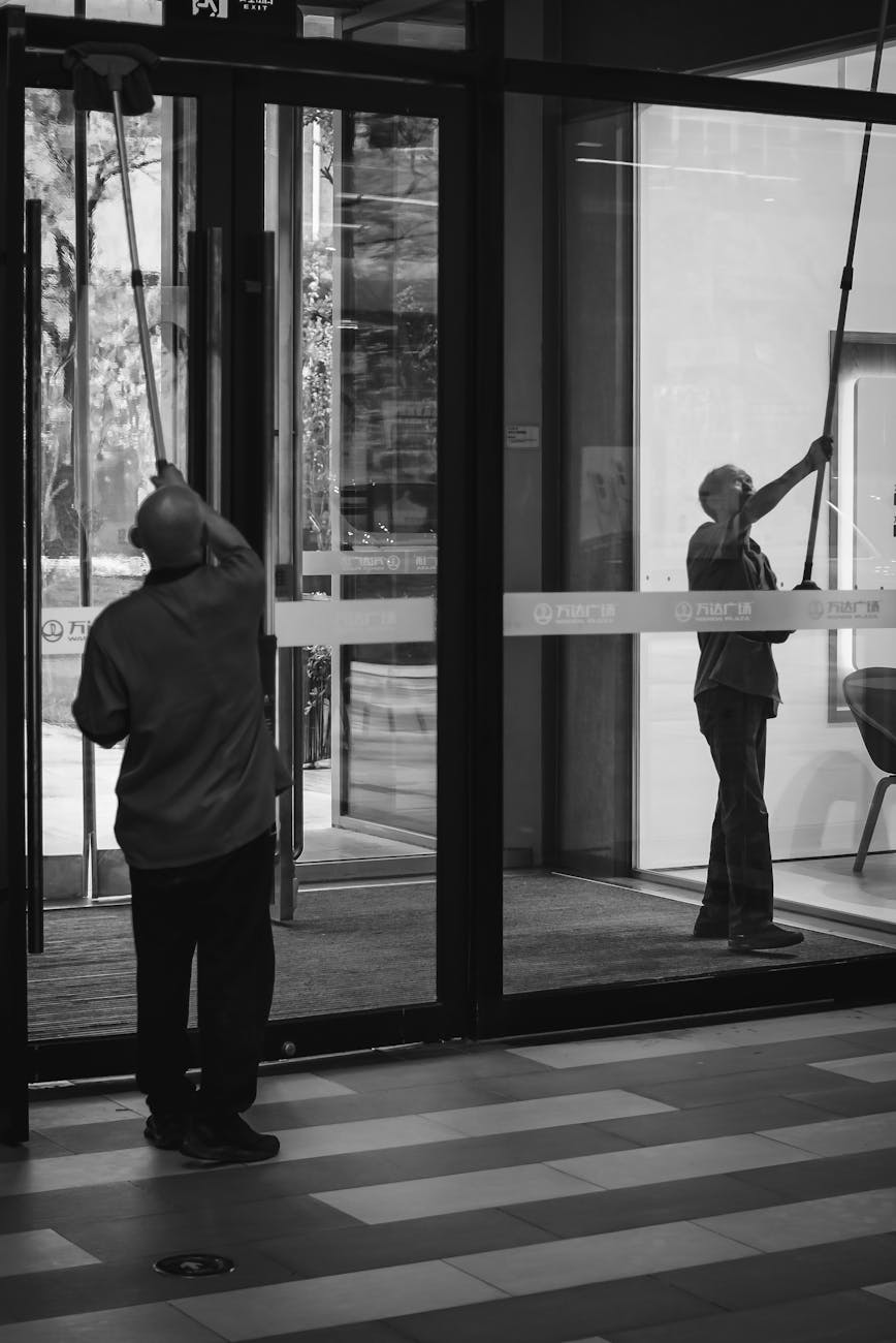 janitors cleaning large glass doors in office building